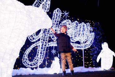 Little boy standing with the lighted sign and sculpture.