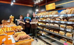 Photo of three workers holding bread in a bakery