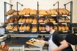 Photo of bread sitting in bakery with man walking in front